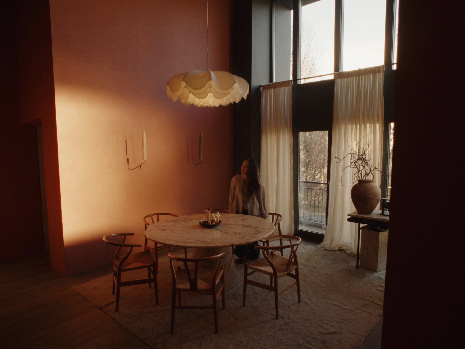 Dining room with round travertine table, oak rush chairs and terracotta wall