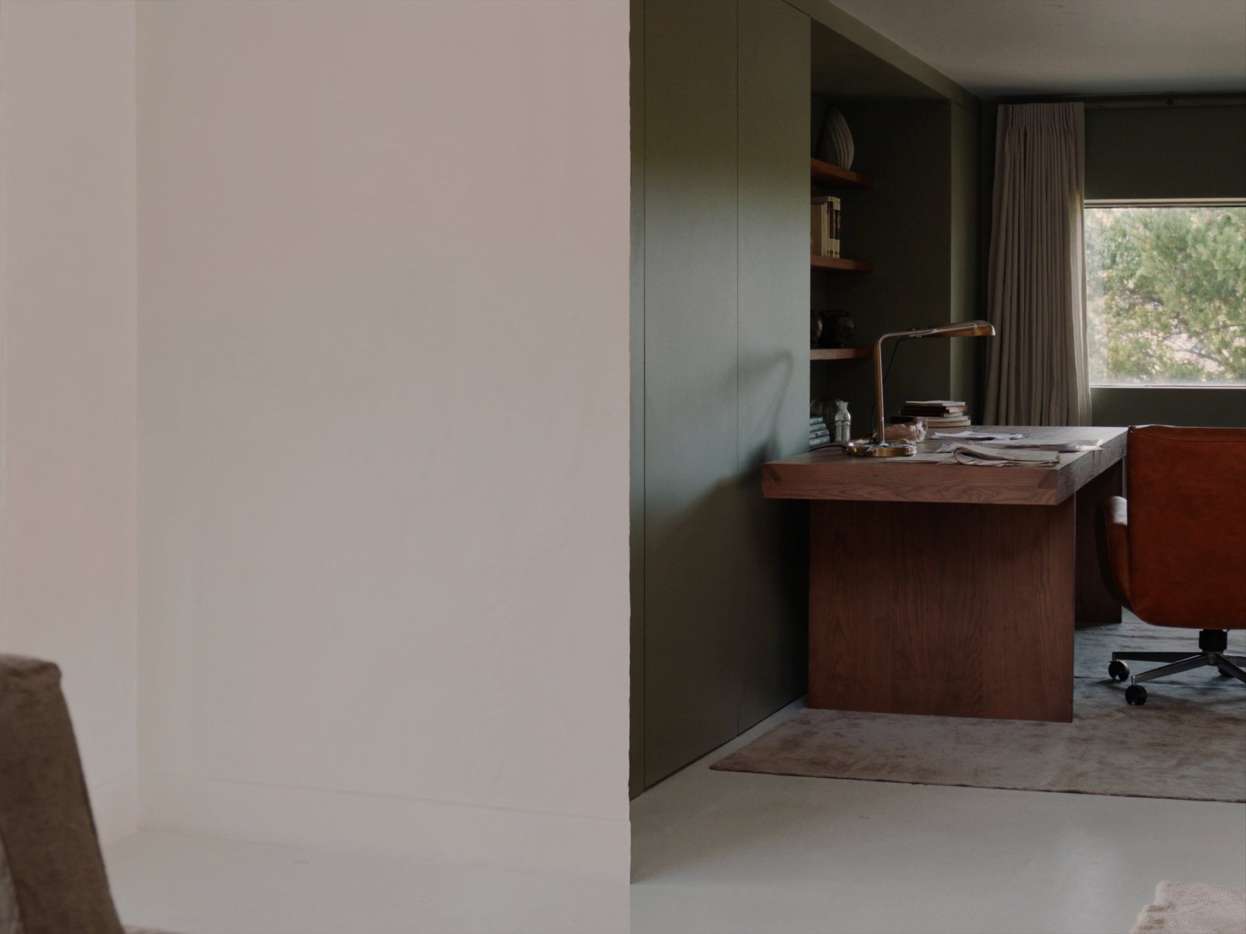 Home office with oak desk, olive built-in shelving and leather chair