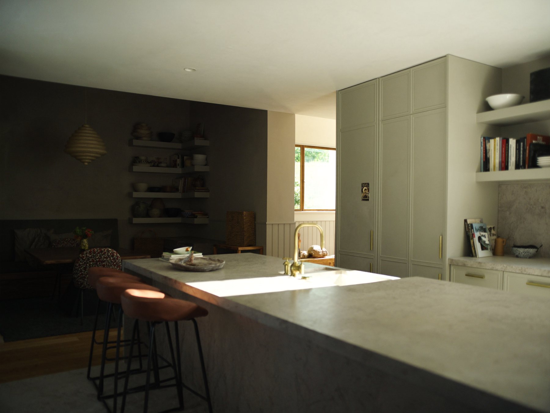 Modern kitchen with olive cabinetry, travertine island and brass fixtures